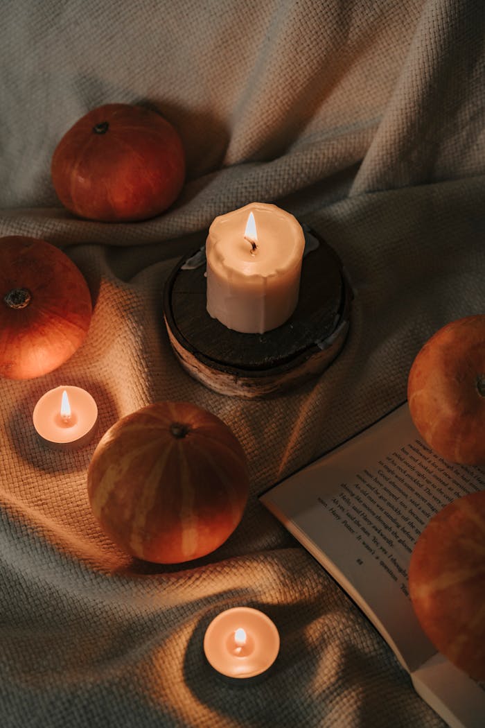 gallery-1 Warm still life featuring lit candles and pumpkins on a textured fabric backdrop, perfect for autumn vibes.