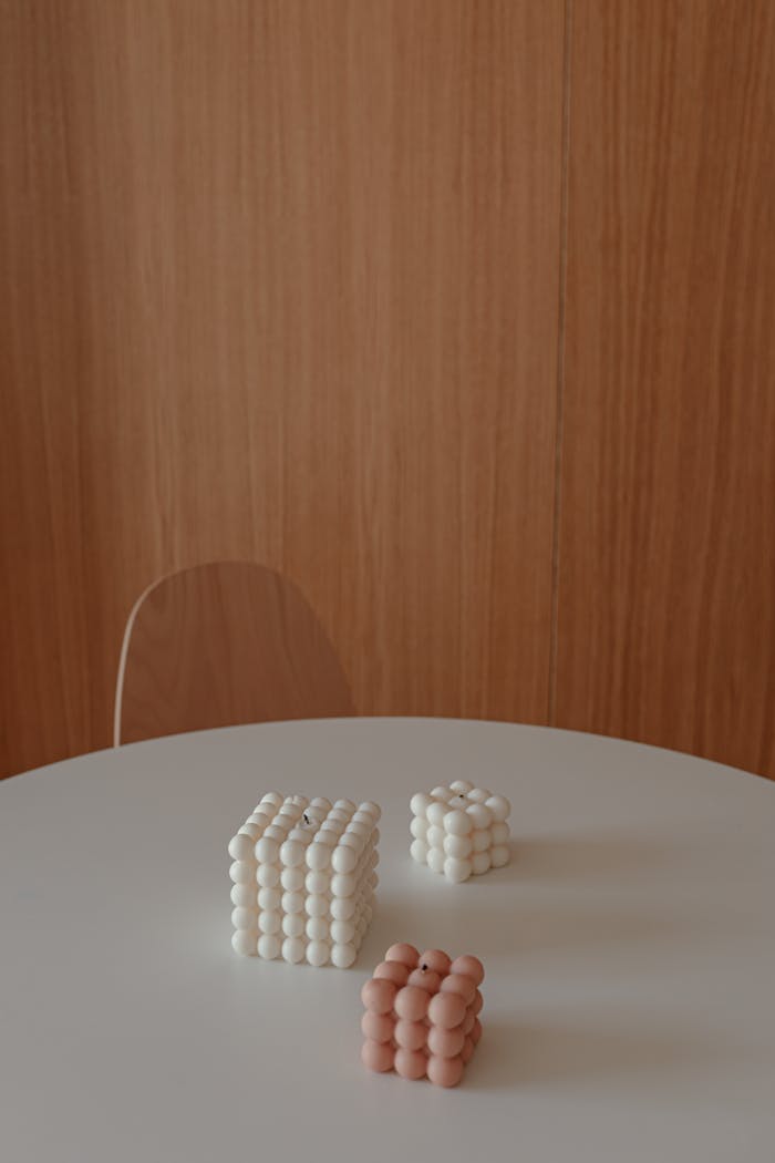 gallery-5 Stylish white and pink decorative candles arranged on a modern minimalist table setting.